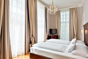 維也納的住宿－維也納美泉宮奧地利時尚公園酒店，一间卧室配有两张床和吊灯。
