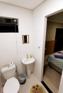 a bathroom with a toilet and a sink and a bed at Acomodações no Jardim Tropical em Rondonópolis in Rondonópolis