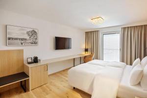 Austria Trend Hotel Maximilian في فيينا: غرفه فندقيه سرير ابيض وتلفزيون