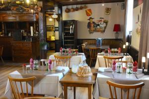 バールにあるア ラ メゾン ルージュ オテル ＆ レストランのテーブルと椅子(白いテーブルクロス付)が備わるレストラン