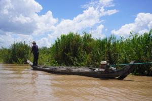 a man standing on a boat in the water at Mechrey Tonle Camp Site in Siem Reap