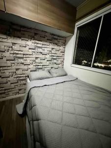 Bett in einem Zimmer mit Ziegelwand in der Unterkunft Apartamento novo linha verde - up life in Curitiba