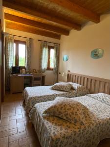 1 dormitorio con 2 camas, escritorio y ventanas en La Casetta di Alessia - Agriturismo con camere, 