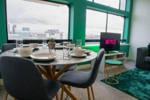 una sala da pranzo con tavolo, sedie e finestre di Manchester City Centre Apartment, Skyline View a Manchester