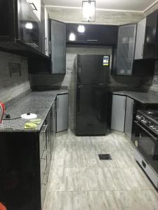 uma cozinha com armários pretos e um frigorífico preto em Gaser resident em Cidade 6 de Outubro