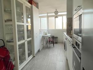 una cocina con armarios blancos y una mesa. en Apartamento Góngora en Sevilla