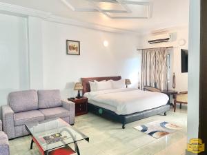 una camera d'albergo con letto e divano di MJ Grand Hotel a East Legon