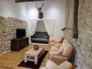 - un salon avec deux canapés et une télévision dans l'établissement Le Grand Cerf - 4 Couchages, à Nalzen