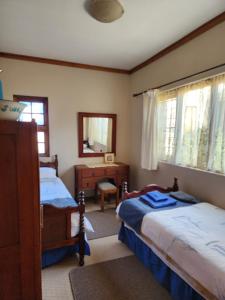 een slaapkamer met 2 bedden, een dressoir en een spiegel bij La Provence Accommodation in Bloemfontein