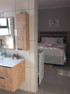 a bedroom with a bed and a sink and a mirror at Serene Cottage in Francistown