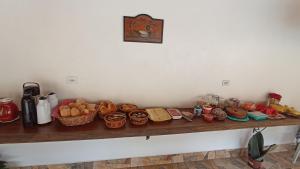 a counter with bread and other food items on it at Pousada Alejandro in Cunha