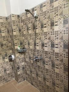 a bathroom with a shower with a tiled wall at Ksf surf house in Uluwatu