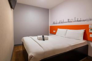 Ce lit se trouve dans un dortoir doté d'un mur orange et blanc. dans l'établissement easyHotel Croydon, à Croydon