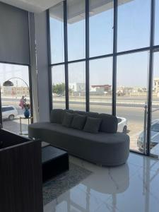a living room with a couch in front of windows at F&M Grand Hotel in Ibri