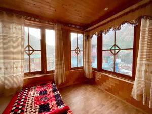 een slaapkamer met ramen en een dekbed bij One Light Stays - Kasol in Kasol
