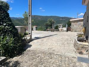 a stone courtyard with a building and mountains in the background at Casa da Lage - Gerês in Vieira do Minho