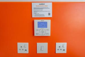 eine orangefarbene Wand mit einem elektronischen Gerät darauf in der Unterkunft easyHotel Croydon in Croydon