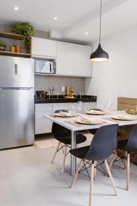 Il comprend une cuisine équipée d'une table, de chaises et d'un réfrigérateur. dans l'établissement Flat luxo Boa Viagem Rooftop 470, à Récife