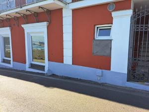 un bâtiment rouge et blanc avec des fenêtres et un portail dans l'établissement Tre Re Appartamento Matima, à Capri