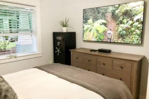 a bedroom with a dresser and a tv on the wall at The 2 Bedroom Jacksonville Blue Bungalow in Jacksonville