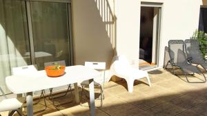 an orange bowl on a white table and chairs on a balcony at Figueira Holidays in Buarcos +1 photo