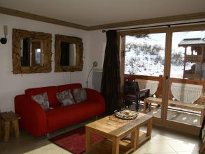 a living room with a red couch and a table at Appartement haut de gamme 3P cabine, pied des pistes, balcon, parking, centre station à 150m - FR-1-557-15 in Les Adrets