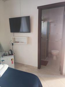 a room with a bed and a television on the wall at Pousada Guesthouse in Timbó