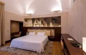 una camera con un letto bianco e un dipinto sul muro di Risorgimento Resort a Lecce