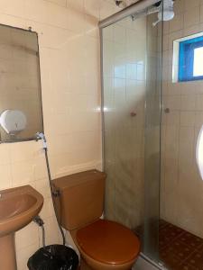 a bathroom with a toilet and a glass shower at Pousada das Tartarugas in Rio das Ostras