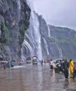a group of people standing in front of a waterfall at Tent City Malshej Junnar Tourism & Farm in Otūr