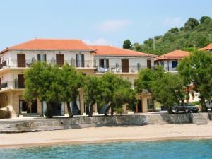 a building on the beach with trees in front of it at Hotel Korakakis Beach in Finikounta