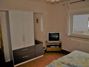 a bedroom with a bed and a dresser and a television at Ferienwohnung Schmidt in Hiddenhausen