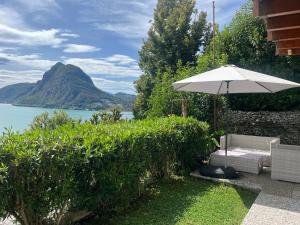 a patio with an umbrella and a table and chair at Lake feelings in Lugano