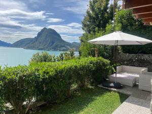 a patio with an umbrella and a bench and water at Lake feelings in Lugano