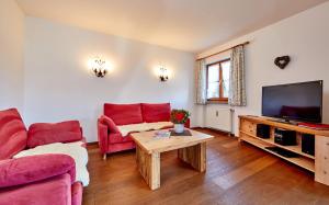 sala de estar con muebles de color rojo y TV de pantalla plana en Appartements Christiane Knöpfle en Oberammergau