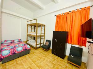 um quarto com uma cama, uma prateleira e uma televisão em Hostal Badillo SV em Cartagena das Índias