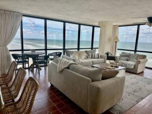 beautiful oceanfront two bedroom condo في دايتونا بيتش: غرفة معيشة مع أريكة وطاولة وكراسي