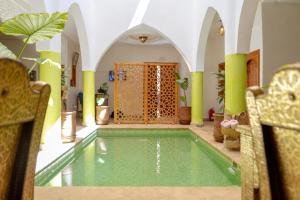una piscina en una habitación con 2 sillas y una habitación con un interior en Riad Petite Rose en Marrakech
