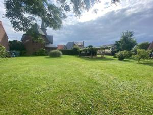 a large grassy yard with a house in the background at Maison Au champ du souvenir 5 chambres 8 personnes in Bécordel-Bécourt