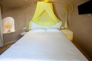 a bedroom with a white bed with a yellow canopy at Golden Sun Hotel in Stelida