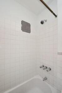 y baño blanco con bañera y ducha. en Beautiful 2BR/1BA in Heart of NYC en Nueva York