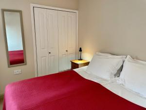 Aleberry Bed and Breakfast في لويس: غرفة نوم بسرير احمر وبيض ومرآة