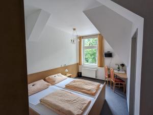 two beds in a room with a desk and a window at Waldgasthaus & Berghotel Steinerne Renne in Wernigerode