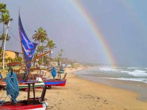 een regenboog over een strand met boten op het zand bij Casinha guagiru in Trairi