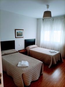 a hotel room with two beds and a window at HOSTAL ALTO PÁRAMO in Villadangos del Páramo