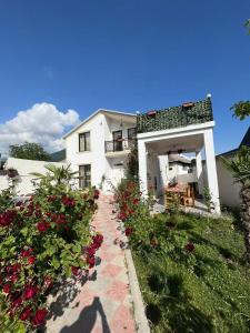 Uma casa branca com flores vermelhas à frente. em Qafqaz mountain white villa em Gabala