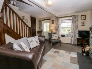 a living room with a leather couch and a television at Rusland View in Ulverston