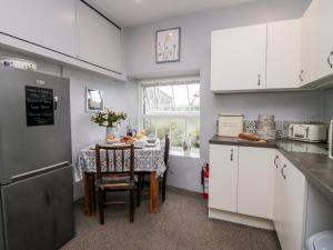 a kitchen with white cabinets and a table with a table cloth at Rusland View in Ulverston