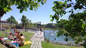 un groupe de personnes assises sur l'herbe près d'un étang dans l'établissement Ferienhof Metzler, à Bodnegg