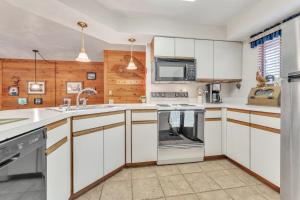 a kitchen with white cabinets and a stove top oven at 7 Springs Ski & Mountain Adventure Condo condo in Champion